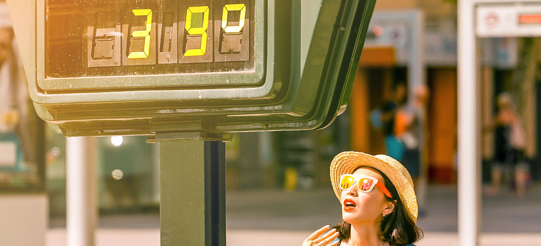Mujer angustiada en la calle al lado de un termómetro con 39 grados